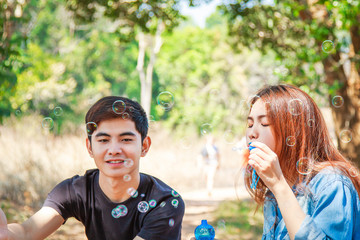 Fototapeta premium Young couple blowing soap bubbles and smiling. Beautiful & Happy family concept.