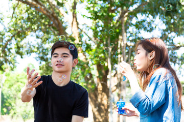 Obraz premium Young couple blowing soap bubbles and smiling. Beautiful & Happy family concept.