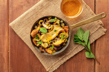 Rustic mushrooms and olives saute with mint and a glass of white wine, shot from the top with copy space