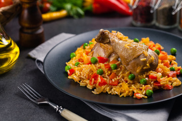 Arroz con pollo. Baked pieces of chicken with bone, rice with paprika and peas.