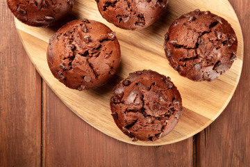 A closeup photo of chocolate chip muffins, shot from above on a dark rustic wooden background with a place for text