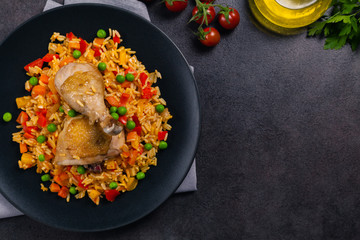 Arroz con pollo. Baked pieces of chicken with bone, rice with paprika and peas.