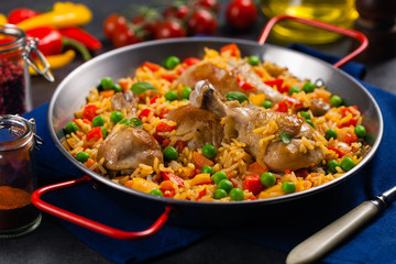Arroz con pollo. Baked pieces of chicken with bone, rice with paprika and peas.