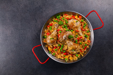 Arroz con pollo. Baked pieces of chicken with bone, rice with paprika and peas.