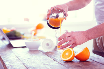 Businessman pouring healthy orange fresh into glass before going to work