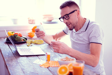 Fototapeta na wymiar Man leading balanced diet holding his morning vitamins having healthy breakfast