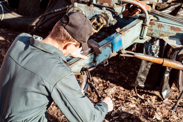 Farmer mechanic repairing agricultural machinery. Male hand holding wrench, repairing combine harvester.