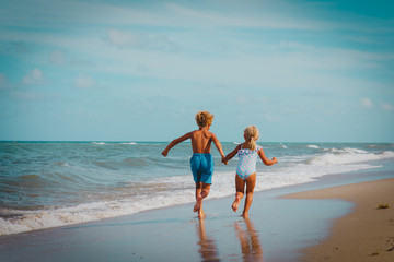kids- boy and girl -running on tropical beach
