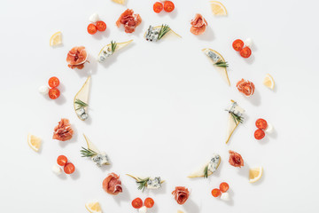 top view of sliced pears with blue cheese and rosemary twigs near prosciutto, cherry tomatoes and mozzarella cheese on white background