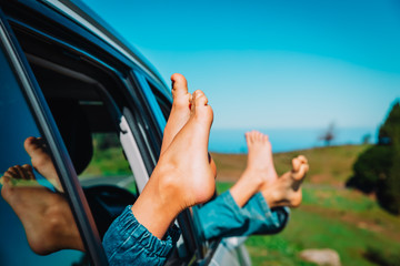 feet of happy kids travel by car in nature