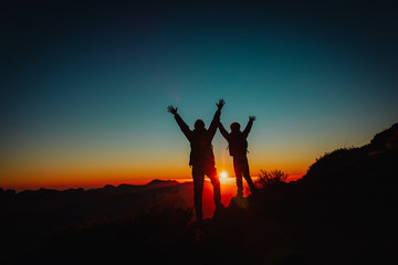 Silhouettes of father and son hiking at sunset, family travel in nature