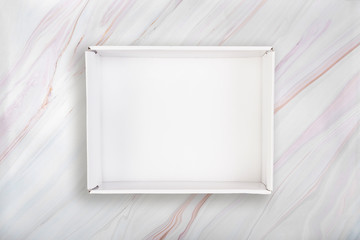 White open box on marble background. Blank white cardboard box on marble texture with natural...