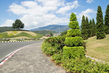 View on an empty road and trees on a hill on a background of mountains on a sunny day. Chiang Mai, Thailand.