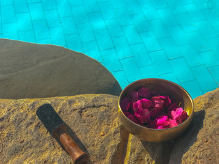 Bronze sound bowl of Tibetan medicine on the shore of the pool stands on an ancient stone. Tibetan...