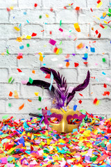 Carnival mask with violet feathers with confetti falling