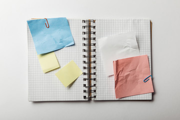 top view of opened notebook with squared papers and sticky notes on white background
