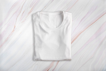 White blank folded t-shirt on marble background texture
