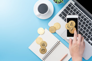 A woman is accounting the money concept isolated on clean blue office working desk with bitcoin and coffee cup, workspace design, mock up, top view, flat lay, copy space, close up
