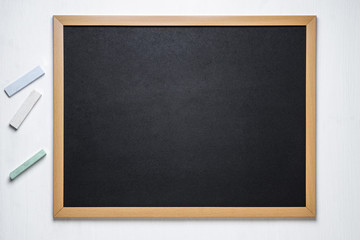 black chalk board and several colored chalk on a white  background