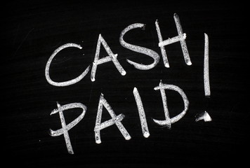 The words Cash Paid written by hand in white chalk on a blackboard as an incentive