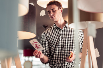 Attractive stylish male surprisingly looking at sale sign tag