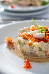 Olivier salad, traditional salad, restaurant dish, salad with shrimp and quail eggs and red caviar, new year's salad,