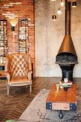 Room in brown tones, with leather, armchair, fireplace and birch wood.