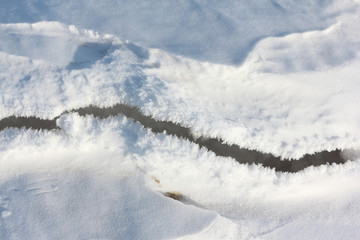 Crack on the snow river in the spring