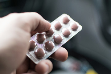 Male hand holds the package with pills.
