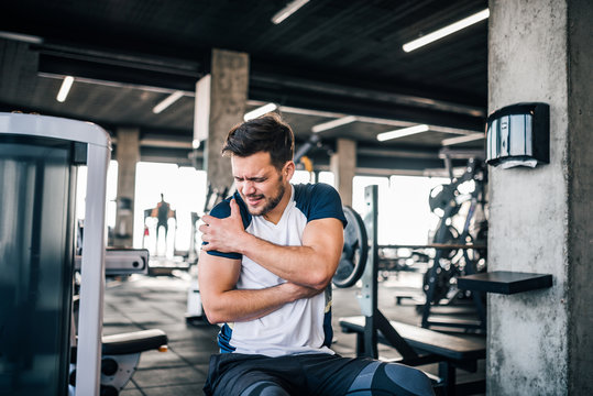 Portrait of a handsome man with strong facial expresion and injured arm while exercising in the gym.