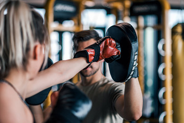 Woman boxer hitting the glove of her sparring partner, close-up. - obrazy, fototapety, plakaty