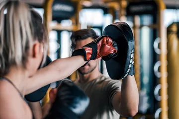 Fotobehang Woman boxer hitting the glove of her sparring partner, close-up. © bnenin