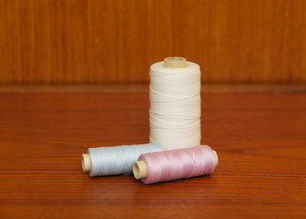Fototapeta na wymiar spools with white, blue and purple threads on the table
