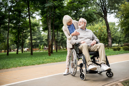 nice senior woman with husband in wheelchair in park