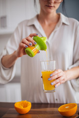 Woman making orange juice in the kitchen