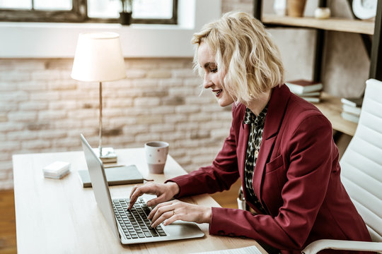 Smiling positive short-haired woman being focused on creating e-mails