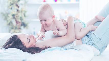 portrait of happy mother and year-old baby on the bed in the bedroom