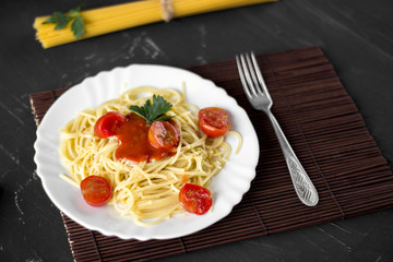 Spaghetti pasta in tomato sauce with cheese and parsley. Italian spaghetti pasta over dark stone background.