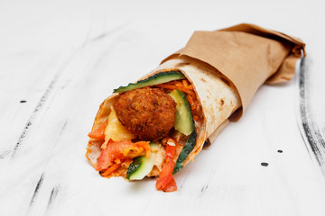 Concept of vegetarian food. Delicious fresh homemade vegetarian tortilla with falafel on a wooden kitchen table. Street food, fast food.