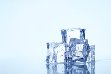 Wet square ice cubes on reflective light blue background. Copy space