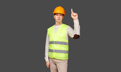 The man the builder in a helmet and a vest points a finger up