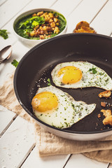 two fried eggs in a pan with herbs and salt for spinach