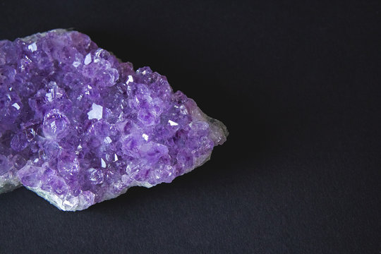 Close-up of amethyst stone druse crystals on dark granite polished slab. Texture of crystals of amethyst. Amethyst crystals geological mineral background. Selective focus
