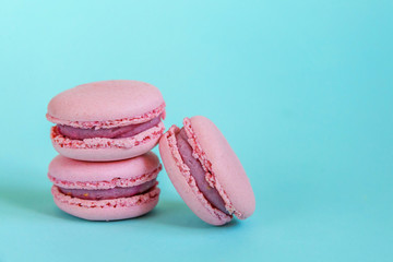 Sweet almond colorful unicorn pink macaron or macaroon dessert cake isolated on trendy blue pastel background. French sweet cookie. Minimal food bakery concept. Copy space