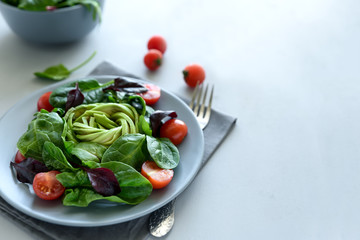 Salad mix with avocado, spinach, tomatoes and beet leaves on gray wooden background. Vegetarian food concept. Selective focus.