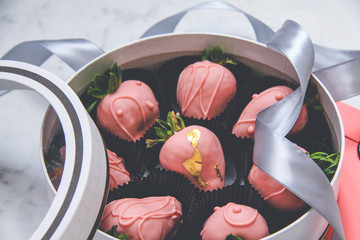 Chocolate-covered strawberries in a gift box with a transparent lid and a gray ribbon and envelope...