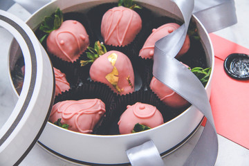 Chocolate-covered strawberries in a gift box with a transparent lid and a gray ribbon and envelope with sealing wax