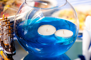 Bright blue water with candles in the glass vase and wooden toy ship. Sea time theme on the party's candy bar