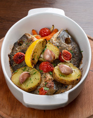 Dorada baked with vegetables in a ceramic bowl