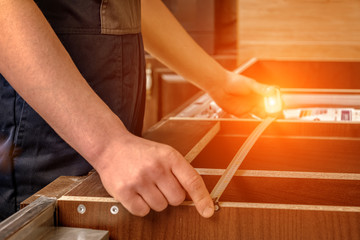 A young worker is assembling modern wooden kitchen furniture.